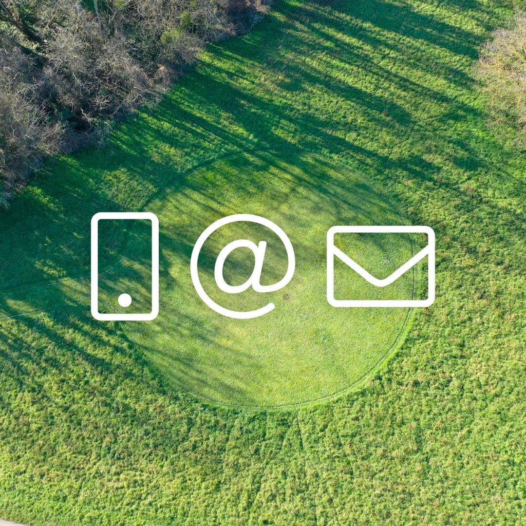 Icônes smartphone, arobase et enveloppe incrustées sur un terrain d'herbe tondu vue depuis un drone